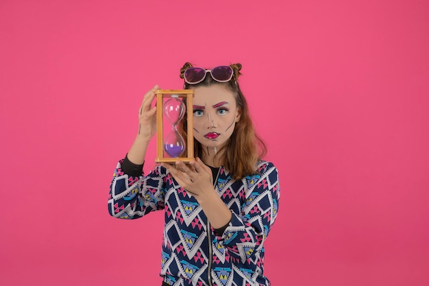 Bianca belle fille portant un maquillage fantastique et tenant une horloge de sable. Photo de haute qualité