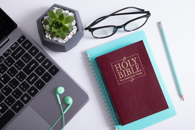 Bible et ordinateur portable sur la table de travail avec des écouteurs. concept en ligne d'étude de la bible