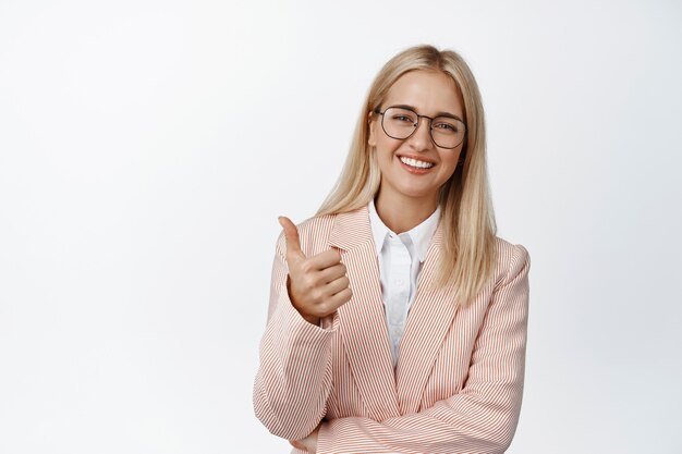 Bien fait. Jeune femme d'entreprise, entrepreneur en costume et lunettes montre des pouces et des sourires heureux sur blanc