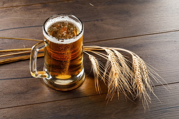 Photo gratuite bière dans une tasse en verre avec épis de blé vue en plongée sur une table en bois