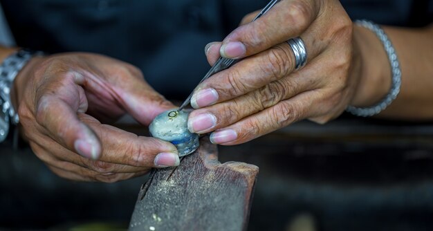 Bijoutier thaïlandais, gère les bijoux et les pierres précieuses dans l'atelier, le processus de fabrication de bijoux, gros plan