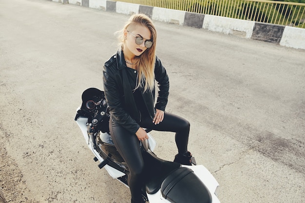 Biker belle femme posant assis sur une moto