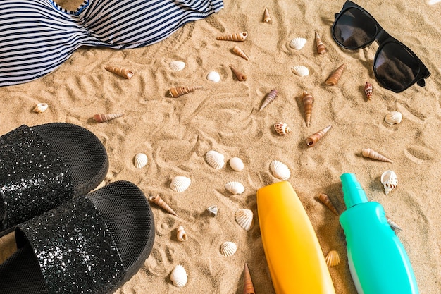 Bikini d'été et accessoires de plage élégants, tenue d'été de bikini de plage et sable de mer en arrière-plan, vue de dessus, concept
