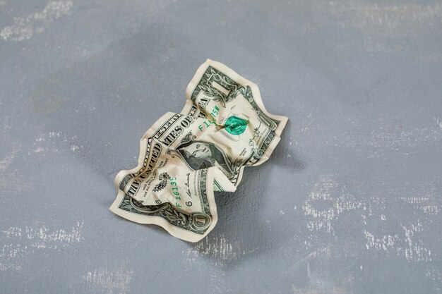 Photo gratuite billet de dollar froissé sur table en plâtre.