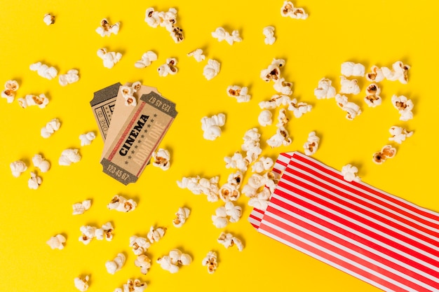 Billets de cinéma sur les pop-corn renversés sur fond jaune