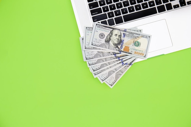 Photo gratuite billets d'un dollar sur un ordinateur portable sur fond vert à plat