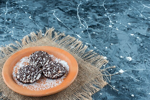 Biscuit au chocolat sur une plaque d'argile sur la texture, sur la table bleue.