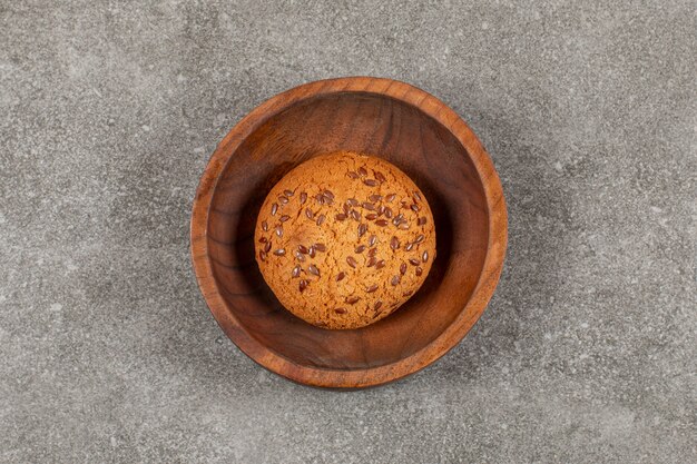 Biscuit fraîchement sorti du four dans un bol en bois sur fond gris.