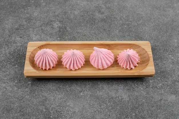 Biscuit de meringue rose frais sur planche de bois sur table grise.