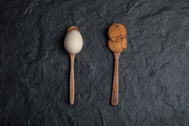 Biscuit et œuf cru sur une surface sombre