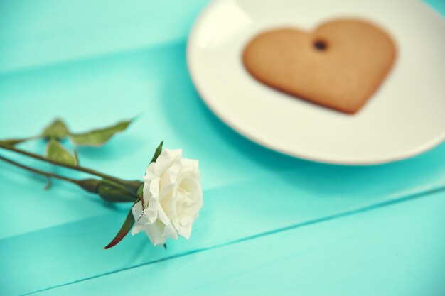 Biscuit de pain d'épice en forme de coeur sur la vue de dessus de plaque blanche Vieille table en bois