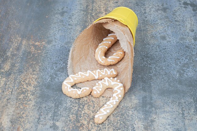 Biscuit sucré de Noël dans un seau jaune sur une table en marbre.