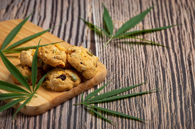 Photo gratuite biscuits au cannabis et feuilles de cannabis mis sur une planche à découper en bois