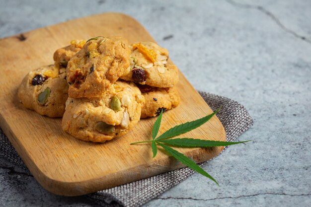 Biscuits au cannabis et feuilles de cannabis mis sur une planche à découper en bois