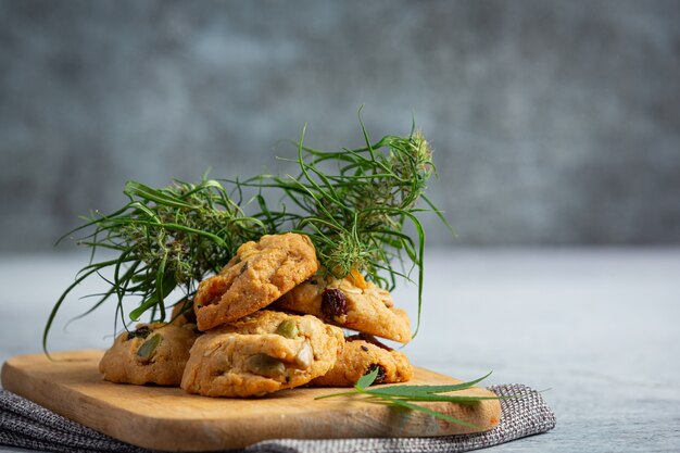 Biscuits au cannabis et feuilles de cannabis mis sur une planche à découper en bois