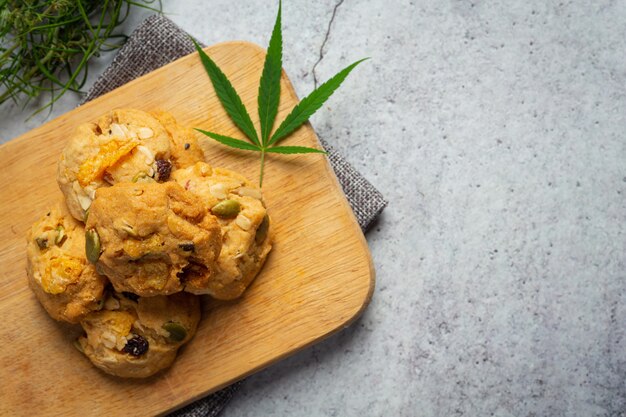 Biscuits au cannabis et feuilles de cannabis mis sur une planche à découper en bois