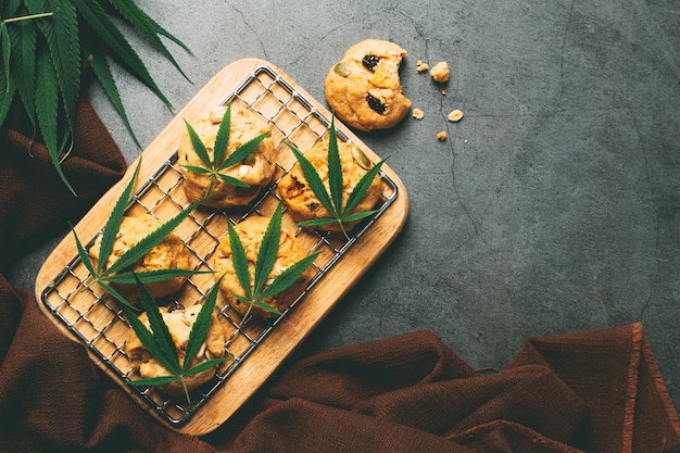 Biscuits au cannabis et feuilles de cannabis mis sur une planche à découper en bois