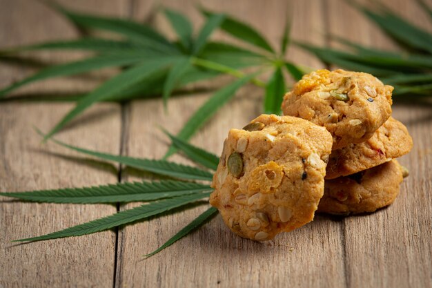 Biscuits au cannabis et feuilles de cannabis mis sur un plancher en bois