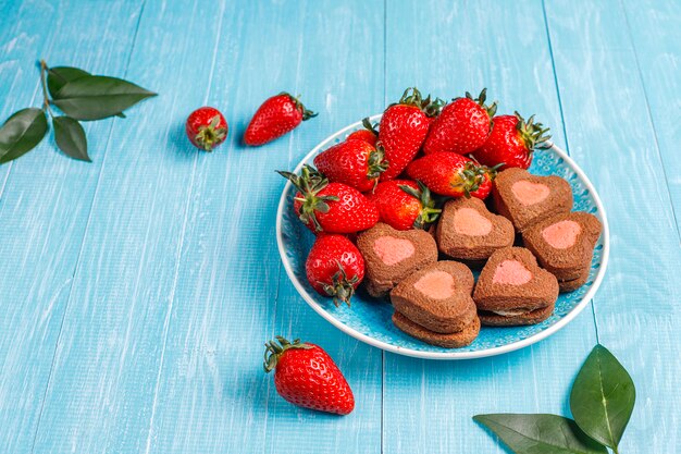 Biscuits au chocolat et aux fraises en forme de coeur avec des fraises fraîches, vue du dessus