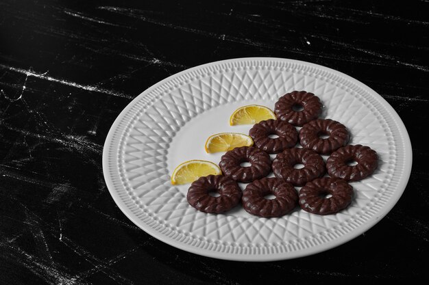 Photo gratuite biscuits au chocolat dans une assiette blanche avec du citron.