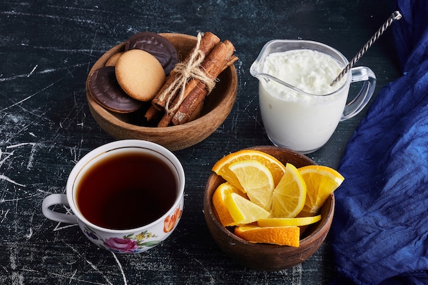 Biscuits au chocolat dans une tasse en bois avec du caillé, du thé et de l'orange.