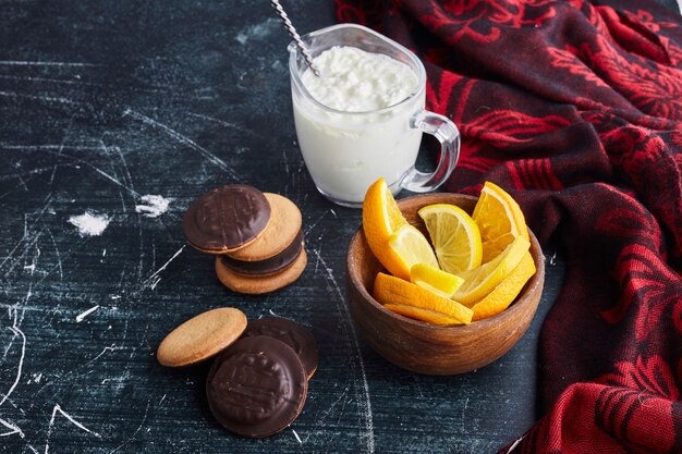 Biscuits au chocolat dans une tasse en bois avec du caillé et de l'orange.