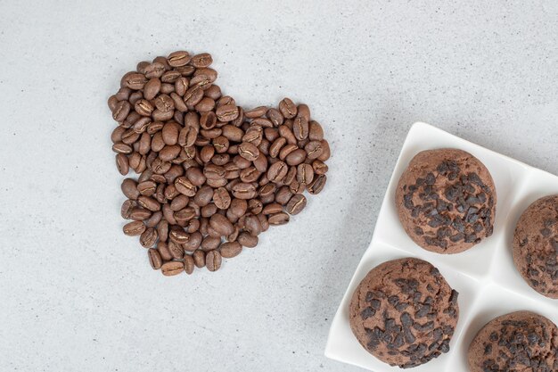 Biscuits au chocolat avec des grains de café sur une surface blanche.
