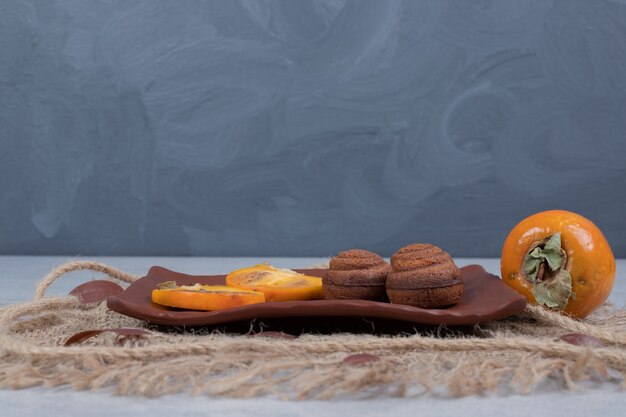 Biscuits au chocolat et tranches de kaki sur assiette. Photo de haute qualité