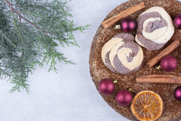 Biscuits aux boules, cannelles et tranches d'orange sur morceau de bois.