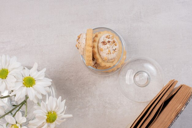 Biscuits à l'avoine et aux raisins secs dans un bocal en verre, livre et marguerites.