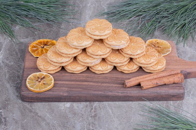 Biscuits avec des bâtons de cannelle et des tranches de citron sec sur une planche de bois