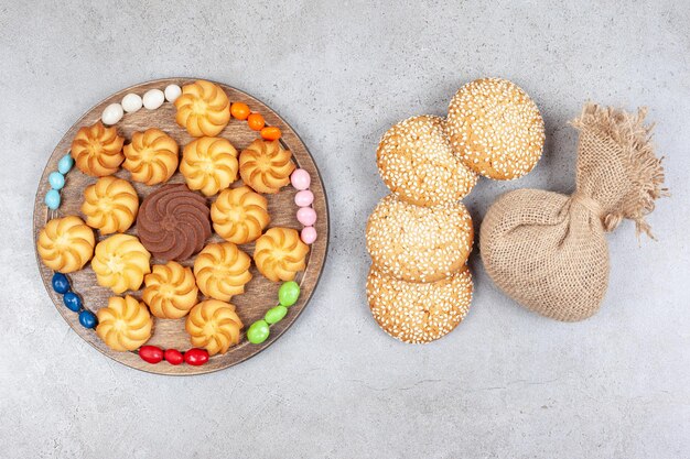 Biscuits et bonbons sur planche de bois à côté de cookies et un sac sur fond de marbre. Photo de haute qualité