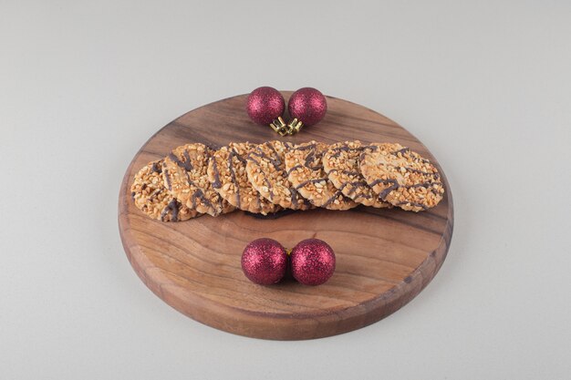 Biscuits et boules de Noël sur une planche de bois sur fond blanc.