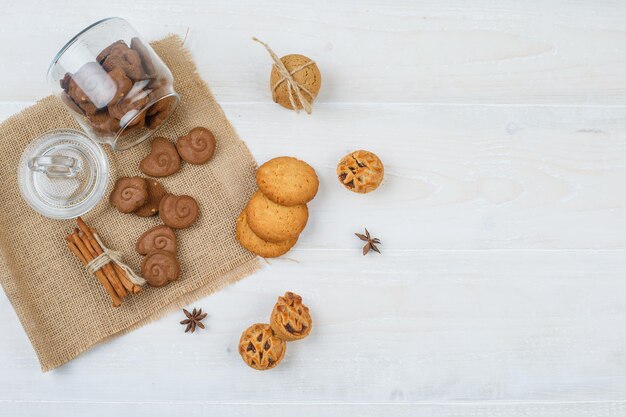 Biscuits bruns dans un bocal,cannelle dans un napperon avec des biscuits blancs