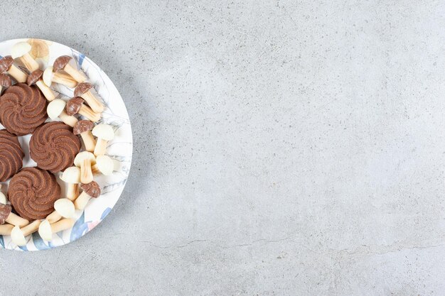 Biscuits et champignons au chocolat sur une plaque sur une surface en marbre