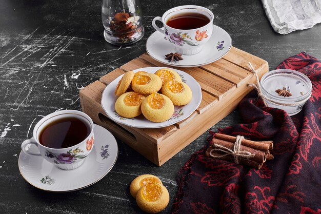 Biscuits à la confiture d'abricots avec deux tasses de thé.