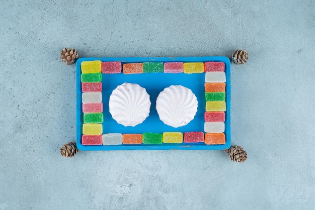 Biscuits et confitures sur un plateau bleu sur marbre.