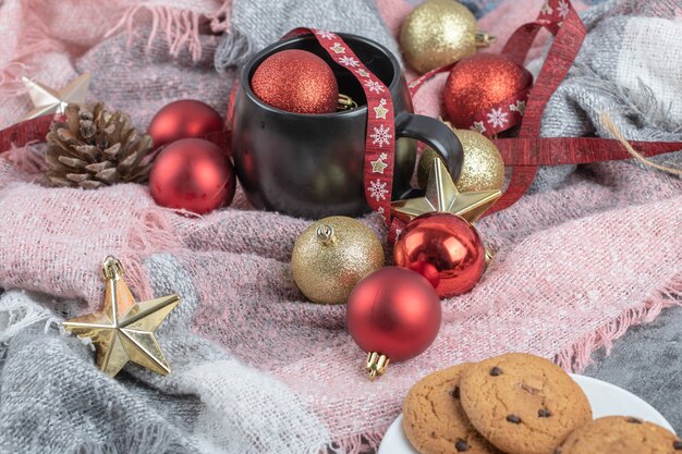 Biscuits croustillants au gingembre dans une soucoupe blanche avec une tasse de boisson et des décorations de Noël autour
