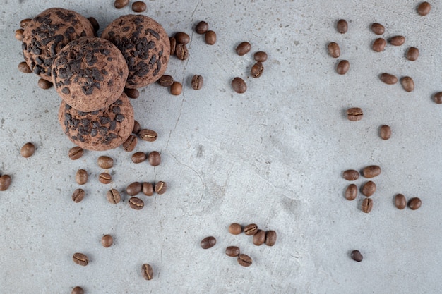 Biscuits délicieux avec garniture aux pépites de chocolat et grains de café éparpillés sur une surface en marbre