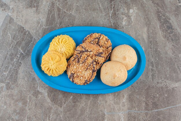 Biscuits divers sur une plaque de bois sur marbre.