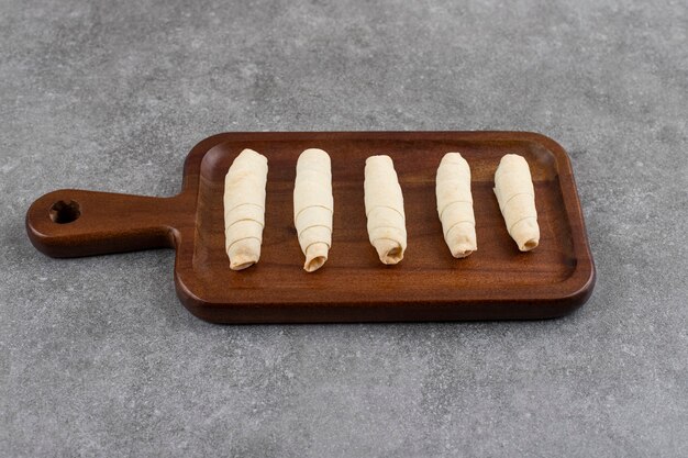 Biscuits faits maison frais roulés sur une plaque en bois sur une surface grise