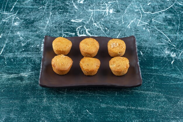 Biscuits faits maison sur une plaque noire, sur la table bleue.