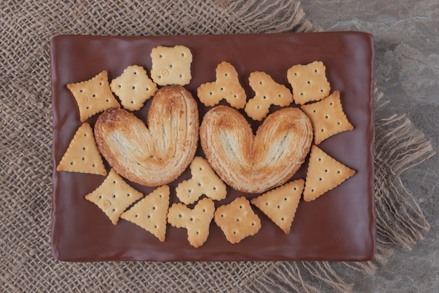 Biscuits feuilletés et paquets de craquelins sur un plateau sur marbre