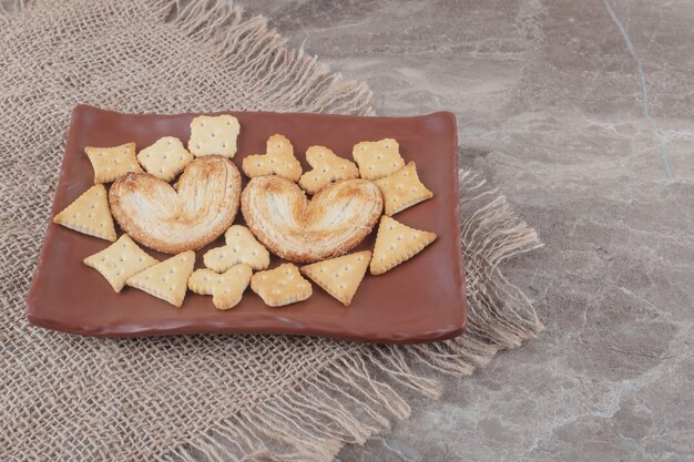 Biscuits feuilletés et paquets de craquelins sur un plateau sur marbre