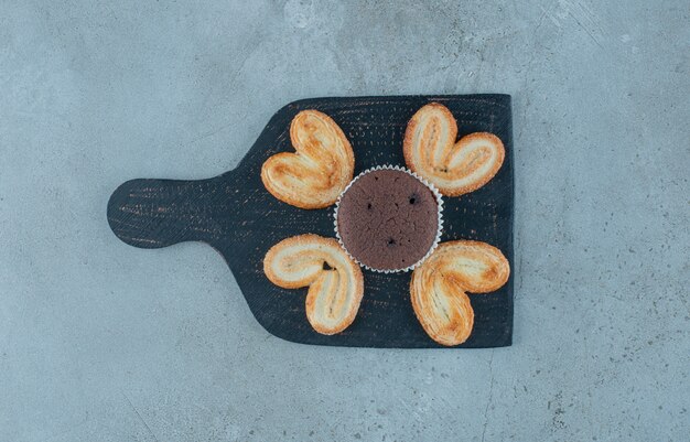 Biscuits feuilletés et un petit gâteau sur un tableau noir sur fond de marbre. Photo de haute qualité