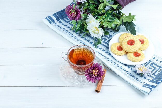 Biscuits, fleurs sur un napperon à la cannelle, tasse de thé