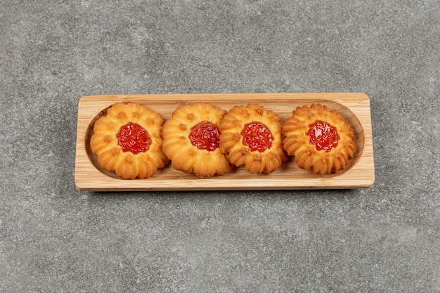 Biscuits en forme de fleur avec de la gelée sur planche de bois