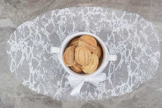 Biscuits en forme de noix dans un bol blanc avec ruban. Photo de haute qualité