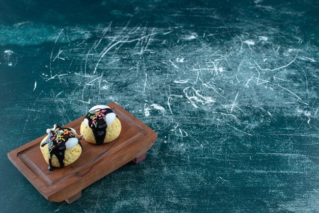 Biscuits glacés faits maison sur une plaque en bois, sur la table bleue.