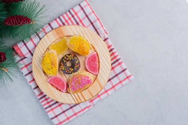 Biscuits de Noël, beignets et marmelades sur assiette sombre.